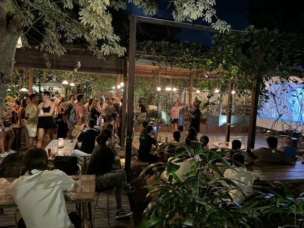 A large crowd in a garden venue in Canggu, facing a big screen