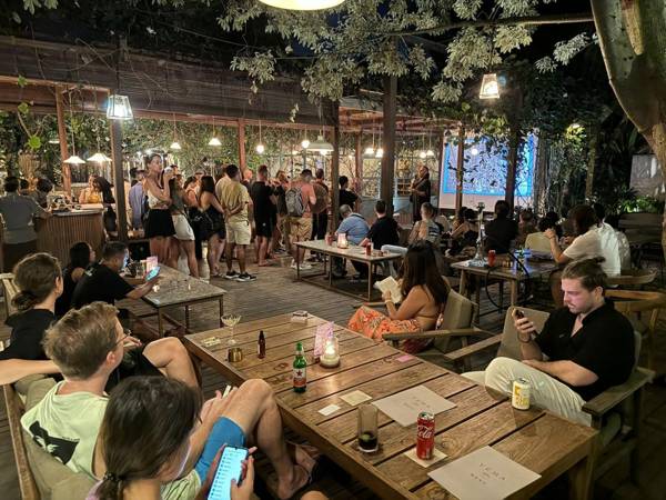 A packed evening crowd standing and sitting around tables